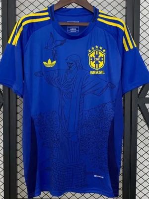  Brasil Adidas t-shirt - Blå t-shirt från Adidas med Brasil-tryck och CBF-logga på bröstet. T-shirten har gula detaljer på axlarna och ett stort tryck av Kristusstatyn på framsidan. Tillverkad i lätt och ventilerande material, perfekt för dig som gillar sportig stil.