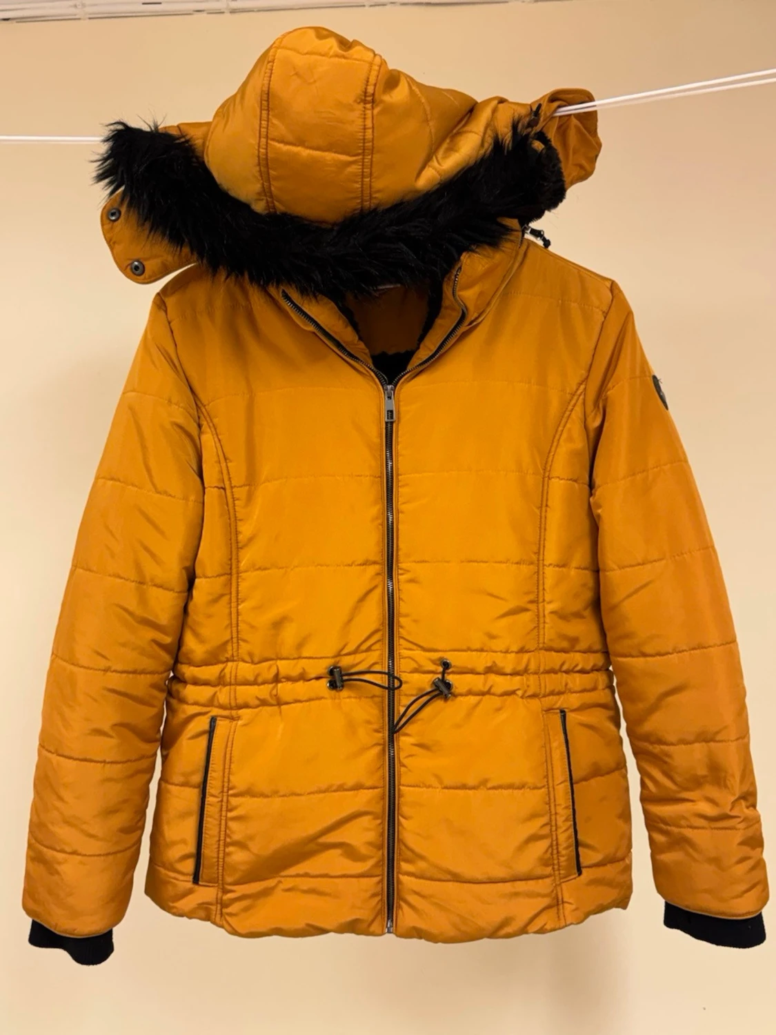 Senapsgul quiltad jacka med svart fuskpäls från Seventyseven. 