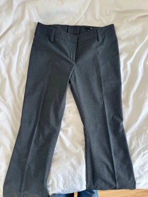 Randiga gråa kostymbyxor hm - Säljer mina skitsnygga lite baggy lågmidjade kostymbyxor från hm! Har tyvärr blivit lite för små för mig så dags att sälja! Köpta second hand men originellt från hm och visar inga defekter! Bara använda några gånger sen jag köpte de! Storlek 40 så skulle säga att de passar perfekt på någon med strl m eller 36/38! Benen är uppsydda men går att sprätta upp utan problem så passar även för någon längre( jag är 173 och de går ner till marken för mig!)