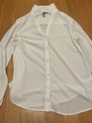 Vit klassisk skjorta med knappar - Stilren vit skjorta med lång ärm och knäppning framtill. Skjortan har en klassisk krage och är tillverkad i ett tunt, lätt material som ger en luftig känsla. Perfekt att styla till olika outfits för en clean look. Pris kan diskuteras 