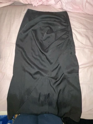 Svart pennkjol i bomull - Klassisk svart pennkjol med enkel design och rak passform. Kjolen är knälång och sydd i mjukt bomullstyg, perfekt för en clean och stilren look. Passar till crop tops eller skjortor för en snygg outfit.