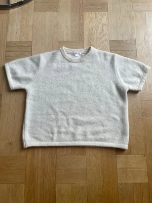 Vit stickad tröja med korta ärmar - En enkel och stilren vit stickad tröja med korta ärmar och rund halsringning. Tröjan har en rak passform och ribbstickade detaljer vid halsen. Perfekt för lager på lager och passar till det mesta i garderoben. Färgen är lite beige vit/ off white. Tröjan är från Gina tricot och i mycket bra skick förutom några få fläckar men det är inget som märks av vid användning. Vid frågor eller funderingar är det bara att säga till Mvh.