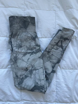 Grå mönstrade leggings från ICANIWILL - Snygga grå leggings från ICANIWILL med marmorerat mönster och hög midja. De har ribbad linning och är tillverkade i ett stretchigt material som sitter tajt och bekvämt. Perfekta för träning eller chill. 