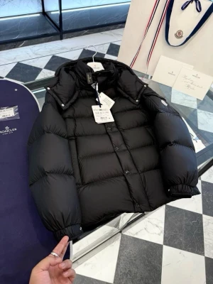 Svart dunjacka från Moncler - Snygg svart dunjacka från Moncler med klassisk puffer-design, hög krage och avtagbar huva. Jackan har tryckknappar och dragkedja framtill samt elastiska muddar vid ärmsluten. Perfekt för kalla vinterdagar och riktigt stilren look.