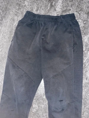 Mörkgrå mjukisbyxor med detaljer - Säljer ett par mörkgrå mjukisbyxor med elastisk midja och snedställda sömmar över benen. Byxorna har fickor på sidorna och är tillverkade i mjukt bomullsliknande material. Perfekta för chill dagar eller när du vill ha det bekvämt.