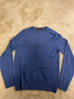 Blå tröja från Morris - Snygg blå rundhalsad tröja från Morris i tunnare stickning. Tröjan har diskret Morris-logga broderad på bröstet och ribbade muddar vid ärmslut och nederkant. Perfekt för lager på lager och enkel att matcha med olika outfits. Pris går att diskutera. Kontakta vid minsta fundering!