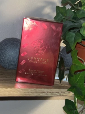 Versace Eros Flame Eau de Parfum - Versace Eros Flame Eau de Parfum i en snygg röd och guldig förpackning. Lådan har en lyxig glansig finish med Versaces ikoniska Medusa-logga och guldtext. Perfekt för dig som gillar exklusiva dofter och vill ha något som sticker ut i parfymhyllan.