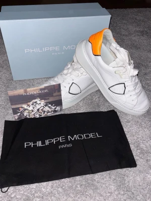 Philippe Model Temple Low - Ett par Philippe Model Temple Low, vita med orange detalj. Nypris: 3000+ kr, mitt pris: 1499 kr. Kan diskuteras vid snabb affär 😉. Strl 43. Skick 8/10. Kartong, dustbag och kort medföljer självklart. Hör av er vid frågor eller om ni vill ha fler bilder! Skickar snabbt 🚚💨