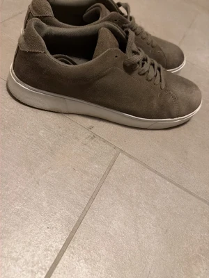 Bruna mockasneakers med vit sula - Snygga sneakers i brun mocka med klassisk låg profil och vita sulor. Skorna har matchande bruna skosnören och en enkel, stilren design som passar till det mesta. Perfekta för dig som gillar en clean och avslappnad look. Skorna är från pier one. Jätte fint skick, knappt använda och inga defekter. Hör av dig vid minsta fråga!😊