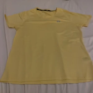 Gul träning t-shirt från Lager157 - Snygg gul t-shirt från Lager 157  med korta ärmar och diskret logga på bröstet. Tillverkad i ett lätt och funktionellt syntetmaterial som passar perfekt för en aktiv livsstil. Enkel och stilren design med normal passform.