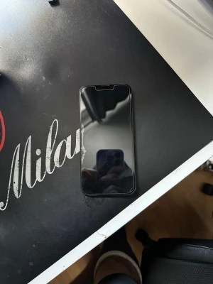 Svart iPhone med Face ID 16E - Säljer en svart iPhone med Face ID och helskärmsdesign. Telefonen har en elegant glasbaksida och aluminiumram. Perfekt för dig som gillar Apples stilrena design och vill ha en mobil med stor skärm och smidiga funktioner.