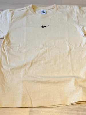 Beige Nike T-shirt storlek S - PRISET ÄR INTE SPIKAT SKRIV VID INTRESSE! Snygg beige t-shirt från Nike med klassisk svart swoosh-logga på bröstet. Tillverkad i mjuk bomull som känns skön mot huden. Enkel och stilren design som passar perfekt till jeans eller shorts.