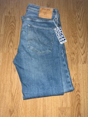 Blå jeans från Jack & Jones - Snygga blå jeans från Jack & Jones med klassisk femficksdesign och läderpatch bak i midjan. Jeansen har en rak passform och är tillverkade i denim med lätt tvättad look. Perfekta för en avslappnad stil. Storlek 29-32. Bara hör av er vid funderingar!😃