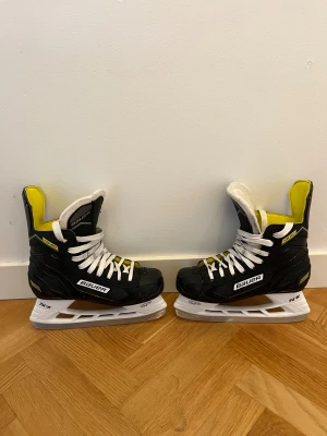 Bauer Supreme s35 hockeyskridskor  - Säljer ett par Bauer supreme s35 hockeyskridskor i svart med gula och vita detaljer. Skridskorna är i storlek 36 och i mycket bra skick.