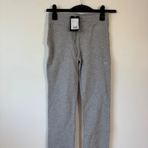 SOC mjukisbyxor - 146/152 Storlek  - Grå mjukisbyxor från SOC i storlek 146/152. Byxorna har en enkel design med elastisk midja och raka ben. Materialet är mjukt och skönt. 