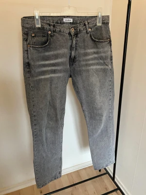 Grå jeans från Woodbird Ourganic -storlek 34/32 - Snygga grå jeans från Woodbird Ourganic Capsule Denim Edition i rak modell. Jeansen har fem fickor, knappgylf och cool tvättad look. Tillverkade i ekologisk bomull för en schysst vibe. Passar dig som gillar klassisk stil med modern touch.