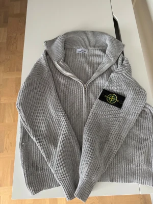 Grå stickad kofta från Stone Island - Säljer en grå stickad Stone Island-halvzip, fint skick som på bilderna. Tröjan är givetvis äkta – badge och tag syns tydligt. Bara att skriva vid minsta fundering eller om du vill ha fler bilder.