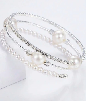 Silverfärgat armband med pärlor och strass - Stilrent armband i silverfärg med flera rader, dekorerat med vita pärlor och gnistrande strass. Armbandet har en spiralform som gör det lätt att ta på och av. Perfekt för dig som gillar en elegant och trendig look.