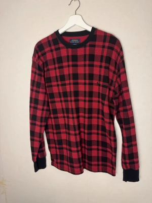 🔥Rutig röd långärmad tröja - Polo Ralph Lauren - 🔥Säljer nu en eftertraktad Polo Ralph Lauren tröja i färgen svart och röd, med det klassiska rutiga mönstret. Tröjan har rund hals med svart kant och är gjord i 100% bomull med en skön, lite grov struktur. Klassisk Polo-logga broderad på bröstet. Perfekt för dig som gillar street och chill stil. 📏Storlek: L ♻️Skick: Mycket bra skick, knappt använd 📊Färg: svart och röd.