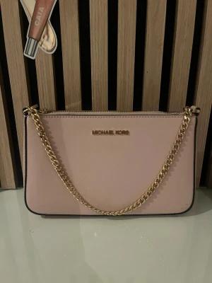 Axelväska Michael Kors  - Snygg ljusrosa axelväska från Michael Kors med guldfärgad kedja och dragkedja upptill. Helt som ny , knappt använd. ❤️