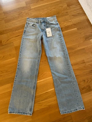 Nya Ljusblå raka jeans midwaist stl 36 - Säljer ett par ljusblå jeans i rak modell med midwaist. Jeansen har klassisk femficksdesign, full längd och är tillverkade i denim. Perfekta för dig som gillar en avslappnad och tidlös look.