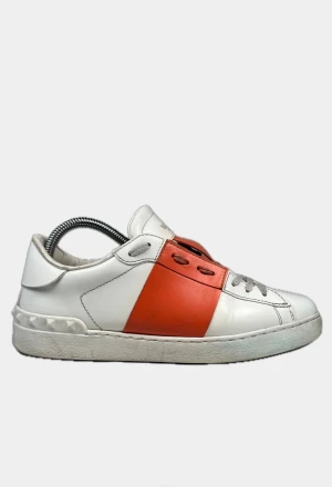 Valentino open skor - Snygga Valentino Garavani Open sneakers i vitt skinn med bred orange läderpanel över mitten. Klassisk rund tå, platt sula och grå snörning. Ikoniska nitar på hälen ger extra edge. Perfekt för dig som gillar exklusiva och trendiga sneakers. Även perfekt till dig som söker riktiga snygga skor👌😃