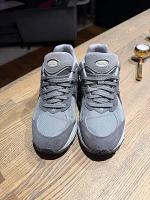 Grå New Balance sneakers - Snygga grå New Balance sneakers med mesh och mockadetaljer. Skorna har rund tå, platt sula och klassisk snörning. Ikoniskt N på sidan och dämpad sula för extra komfort. Perfekt för dig som gillar stilrena och sportiga sneakers.