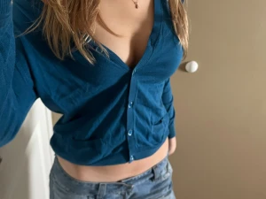 Blå kofta  - Snygg blå croppad kofta med v-ringad hals och knappar framtill. Tröjan har långa ärmar och två små fickor framtill. Perfekt för dig som gillar en chill och trendig stil. Materialet känns mjukt och lätt, troligen bomull eller polyester.