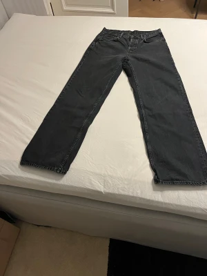 Svarta jeans från Nudie Jeans - Säljer ett par svarta jeans från Nudie Jeans med klassisk femficksdesign och broderad bakficka. Modell Tuff Tony. Jeansen har baggy passform och är tillverkade i kraftigt denimtyg. 