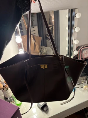 Stor brun väska🤎 - Snygg och rymlig brun axelväska i skinnimitation med långa smala axelband och guldfärgad låsdetalj framtill. Säljer på grund av dubbletter. 500 nypris💕