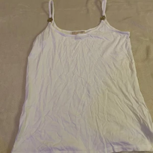 Vitt linne - Michael kors  - Säljer ett vitt linne från Michael Kors i storlek M. Linnet har små fina Michael Kors-detaljer och är lite skrynklig, men går enkelt att stryka. I övrigt i mycket fint skick.🩷