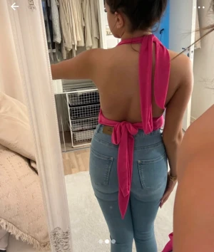 Rosa omlott halterneck topp - Säljer en snygg rosa halterneck topp med omlott och knyt i ryggen. Toppen är croppad och har en draperad v-ringning framtill. Materialet känns mjukt och stretchigt, perfekt för dig som vill ha en cool och trendig look.