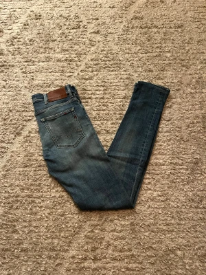 Replay Jondrill jeans  - Hej jag säljer ett par Replay Jondrill jeans med unika slitningar i riktigt snygg blå färg perfekt för dig som vill ha ett par kvalitetsjeans med grym passform, jeansen är i stretch material så otroligt bekväma. Nypris ≈ 1700kr, mitt pris 399kr. Skick: 9/10 Storlek: W30L34 Midja: 38cm Lår: 20cm  Ytterlängd: 110cm Innerlängd: 85cm. Skriv gärna om du vill ha fler bilder eller har frågor!