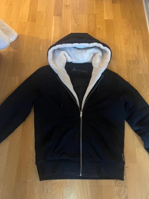 Svart Moose Knuckles jacka bunny  - Svart jacka från Moose Knuckles med vit fluffig fuskpäls i huvan. Jackan har dragkedja framtill, huva med snörning och en snygg logga på ärmen. Praktisk känguruficka och quiltad insida. Perfekt för vintern. Skick 8/10. Köpt för 4999kr på NK förra året. Mitt pris 2400. Vid snabbaffär kan gå ner några hundra. Storlek M. Vid intresse eller frågor skriv!