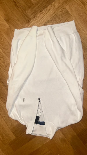 Vit quarter zip tröja från Polo Ralph Lauren - Säljer en vit långärmad tröja från Polo Ralph Lauren med half zip framtill och klassisk broderad logga på bröstet. Tröjan är stickad i bomull och har en stilren, normal passform. Perfekt för dig som gillar clean och tidlös stil. Helt oanvänd. Pris kan diskuteras vid snabb affär.  
