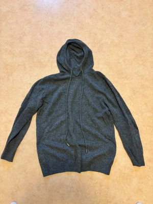 Mörkgrå stickad hoodie  - Mjuk och skön mörkgrå hoodie med huva och snörning. Storlek M men passar även S.