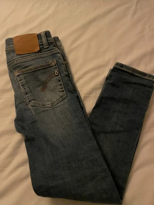 Blå jeans från Dondi Ritchie - Snygga blå jeans från Dondup  med klassisk femficksdesign och slitningar framtill. Jeansen har normal passform och raka ben, med detaljerade sömmar och en brun läderpatch bak i midjan. Perfekt för dig som gillar en avslappnad stil.
