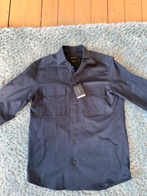 Mörkblå overshirt från Massimo Dutti - Oanvänd mörkblå overshirt från Massimo Dutti i storlek S, men sitter som en M. Hör av dig vid frågor och funderingar. Mhv