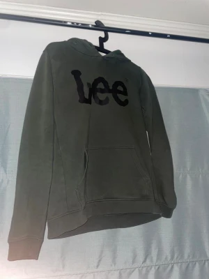 Mörkgrön Lee hoodie med tryck - Säljer en mörkgrön hoodie från Lee med svart logotyptryck på bröstet.  I storlek M/S