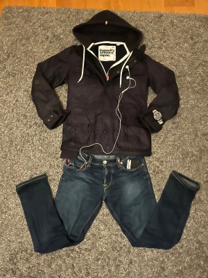 Marinblå quiltad Barbour jacka - Mqrinblå quiltad jacka från Barbour Jackan har två stora fickor framtill med knappar Perfekt för dig som gillar streetwear och vill ha en stilren look med coola detaljer.