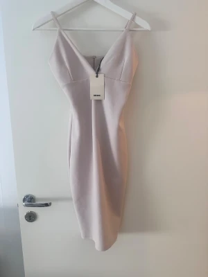 Ljusbeige v-ringad klänning Bik Bok - Supersnygg ljusbeige klänning från Bik Bok med v-ringad hals och smala axelband. Klänningen har en figurnära passform och är knälång, perfekt för dig som gillar stilrena och eleganta plagg. Materialet känns mjukt och har en lätt stretch.