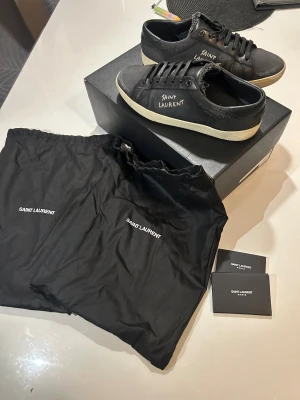 Ysl Skor - Skick 8/10, limmat på sidorna, båda skor. Väldigt bra skick. Storlek 40, passar mig som har 41. Givetvis autentiska, köpte från miinto. Kan kolla efter kvittot om jag hittar det. Bytte snören, så helt nya snören. Allt og medföljer. 2099