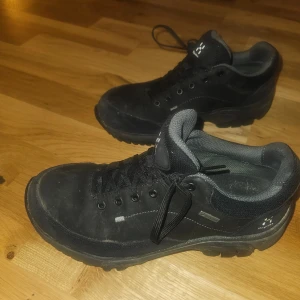 Svarta Haglöfs sneakers med Gore-Tex - Svarta sneakers från Haglöfs med robust platt sula och snörning. Skorna har en rund tå och är tillverkade i slitstark syntet och skinn med Gore-Tex-membran för extra vattentålighet. Perfekta för dig som gillar outdoor och vill ha bekväma skor med bra stöd.
