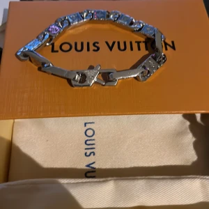 Louis Vuitton silverfärgat armband - Exklusivt armband från Louis Vuitton Monogram World Tour. Kedjan är i silverfärgad metall med ingraverade LV-monogram och detaljer. Snygg och chunky design som sticker ut och ger en lyxig känsla till din outfit.