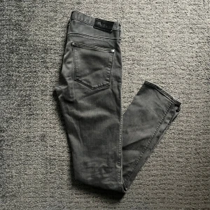Grå jeans från Acne Studios - Säljer ett par gråa skinny jeans från Acne Studios. Jeansen har silverfärgade nitar och knapp, samt Acne-logga på bakfickan. Snygga och bekväma brallor. Storlek 30/34