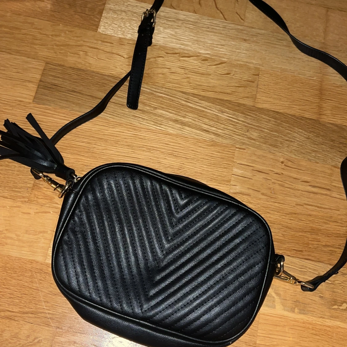 Svart axelväska med tofsdetalj