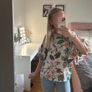 Blommig blus med volangärm från H&M - Superfin blus från H&M i storlek 34 med blommönster. Blusen har vida volangärmar och en lös passform, perfekt för dig som gillar plagg med färg och mönster.