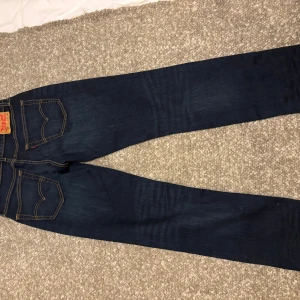 Levi's 541 mörkblå jeans - Mörkblå Levi's 541 jeans med klassiska kontrastsömmar och femficksdesign. Jeansen har en slim passform och är tillverkade i slitstarkt denim med snygg tvätt. Perfekta för dig som gillar en stilren och tidlös look. Storlek W31 L34.
