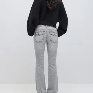 Grå bootcut jeans från Gina - Snygga grå jeans med bootcut passform och markerade sömmar. Byxorna har två bakfickor med lock och knappdetaljer. Perfekta för dig som gillar en klassisk men trendig look.