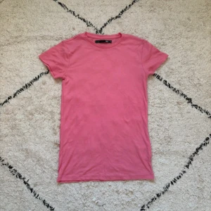 Rosa t-shirt från lager 157 i bomull XS - Enkel och snygg rosa t-shirt från lager 157 i storlek XS. Modellen är klassisk med rund halsringning och korta ärmar. Tillverkad i mjuk bomull som känns skön mot huden. Perfekt att matcha med jeans eller shorts för en chill look.